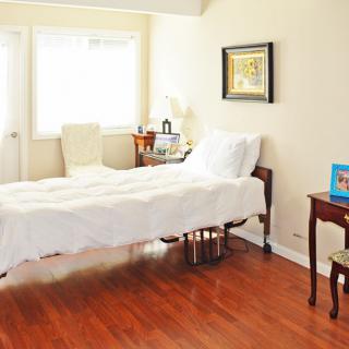 A cozy bedroom with natural lighting, featuring a single bed, wooden flooring, and elegant decor.