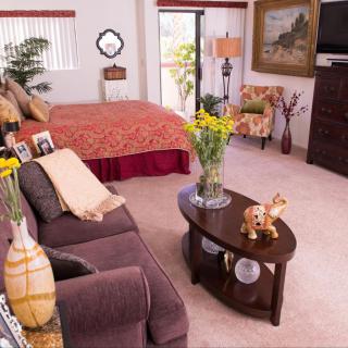 A cozy bedroom with a bed, sofa, and coffee table, adorned with decorative items and artwork.