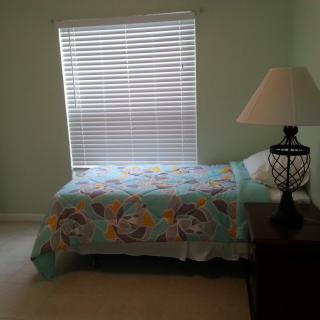 A cozy bedroom with a single bed and a bedside lamp next to a window.