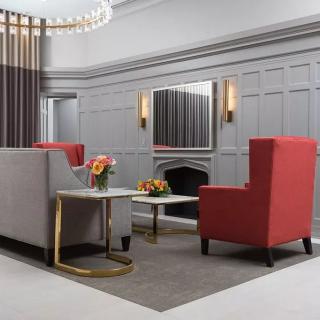 A modern living room featuring red chairs, a grey sofa, and a coffee table with floral centerpieces.