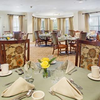 A well-arranged dining room with elegantly set tables and floral centerpieces.
