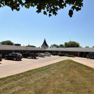 A view of a building with a parking lot under a clear blue sky.