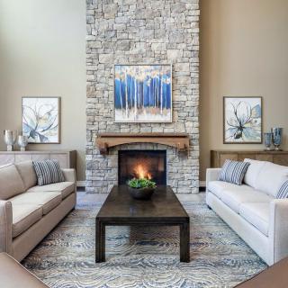 A cozy living room with a stone fireplace, featuring modern decor and neutral-colored sofas.