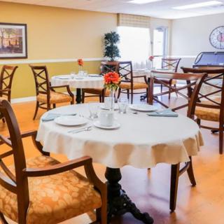 An elegant restaurant dining area with neatly set tables adorned with a flower vase.