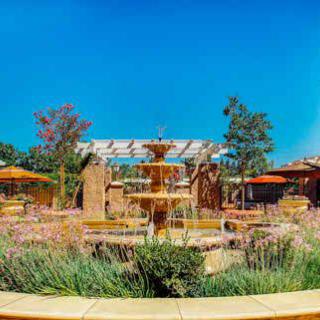 A beautiful garden with a central fountain surrounded by lush greenery and seating areas.