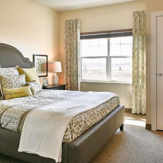 A cozy bedroom interior with a neatly made bed and a window letting in natural light.