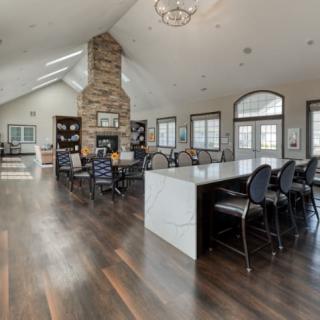 A modern open-concept living space featuring a stone fireplace, hardwood floors, and a spacious kitchen island.