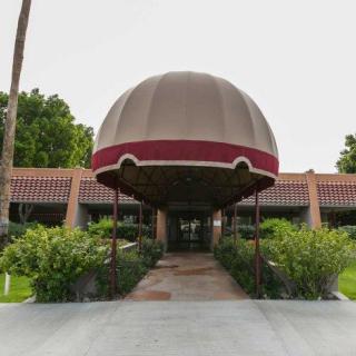 A building entrance with a large dome-shaped canopy and surrounding greenery.