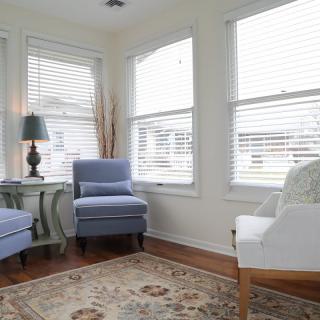 A cozy living room with armchairs, a decorative rug, and natural light streaming through the windows.