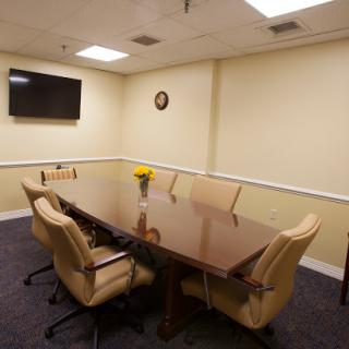 A well-furnished conference room equipped with a large table, chairs, and a television for meetings.