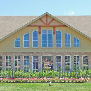 A large house with prominent windows and a well-maintained garden in the foreground.