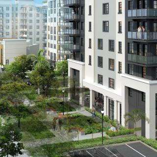 A view of modern apartment buildings with a landscaped green space and parking lot.
