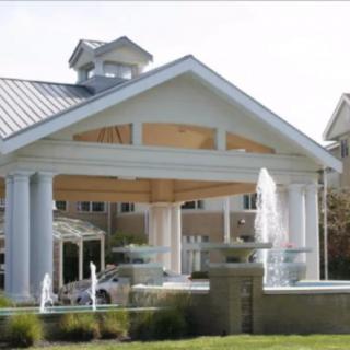 A grand entrance of a building featuring large white columns and a gabled roof.
