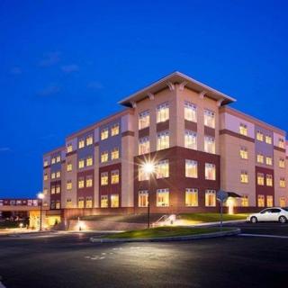 A well-lit building at night with a clear sky and a parking area in the foreground.