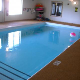 An indoor swimming pool with clear water and a beach ball floating on the surface.