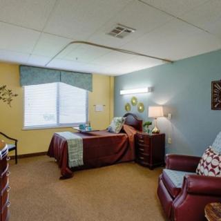 A cozy bedroom with a single bed, armchair, and nightstand.
