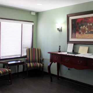 A cozy waiting room with two chairs, a table, and a framed painting on the wall.