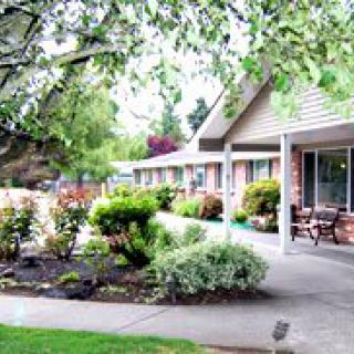 A serene outdoor view of a building surrounded by lush greenery and well-maintained landscaping.