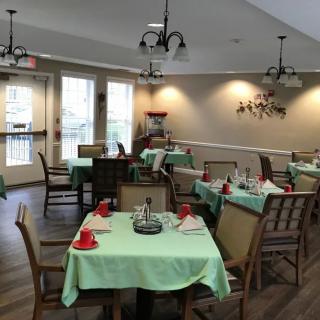 A cozy dining room with tables set with green tablecloths and red cups.