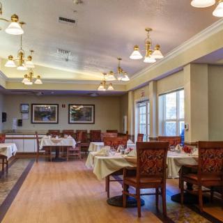 An elegant dining area with neatly arranged tables and chairs, softly lit by overhead lights.