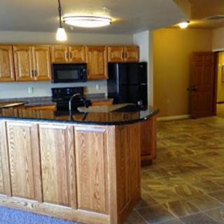A modern kitchen with wooden cabinets, black appliances, and granite countertops.