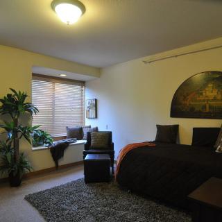 A cozy bedroom with modern decor, featuring a large bed, a window seat, and ambient lighting.