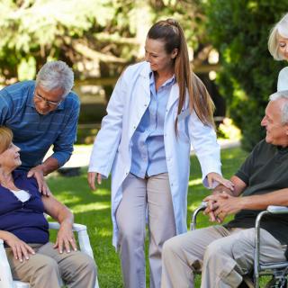 A caregiver engaging with elderly individuals outdoors.