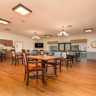A spacious dining area featuring wooden tables, chairs, and ample natural light.