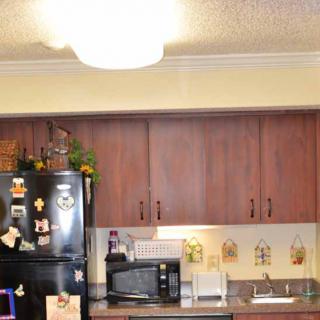 A kitchen featuring wooden cabinets, a black refrigerator, and various appliances on the countertop.