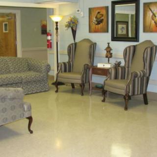 A cozy living room with a sofa and two armchairs arranged around a small table, decorated with artwork and a floor lamp.