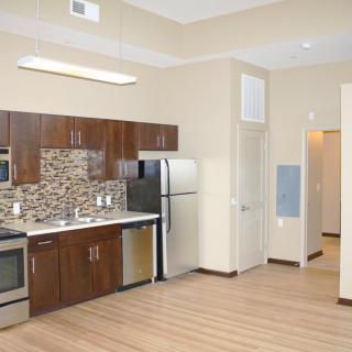 Modern apartment kitchen with wood flooring and stainless steel appliances.