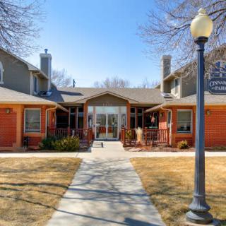 A residential building with a central entrance, flanked by trees and a lamp post along the pathway.