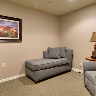 A cozy living room corner featuring a gray couch, wall art, and a table lamp.