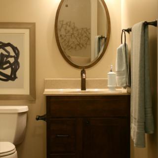 A cozy bathroom with a wooden vanity, oval mirror, and minimalist decor.