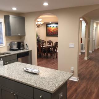 A modern kitchen with an island and adjacent dining area, featuring open space and wood flooring.