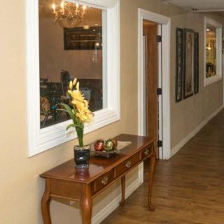 A hallway with a wooden table, decorative flowers, and mirrors on the wall.
