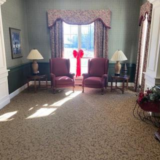 A cozy living room with two chairs by a window adorned with a large red bow.