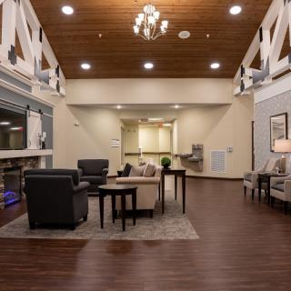 A spacious and elegantly designed lobby with comfortable seating, warm lighting, and a wooden floor.