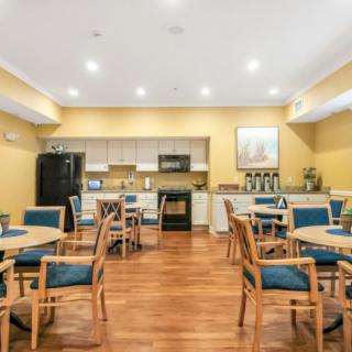 A cozy dining area featuring multiple tables and chairs, with a kitchen in the background equipped with appliances.