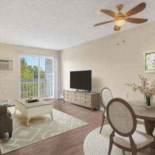 A bright and modern living room with a dining area, featuring a sofa, coffee table, television, and ceiling fan.