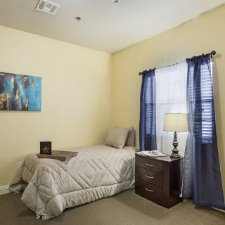 A cozy bedroom with a single bed, nightstand, and soft lighting.