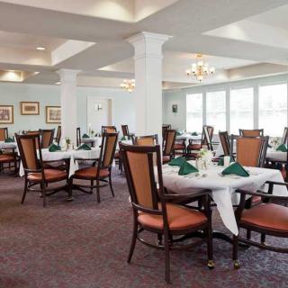 An elegant dining room setup with tables and chairs arranged neatly, ready for guests.
