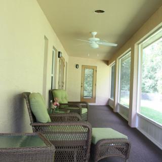 A cozy porch with comfortable chairs and large windows providing a view of the outdoors.