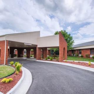 A modern building entrance with a covered driveway and well-maintained landscaping.