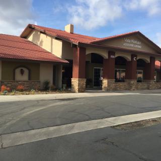 A commercial building with a red roof and stone accents under a partly cloudy sky.