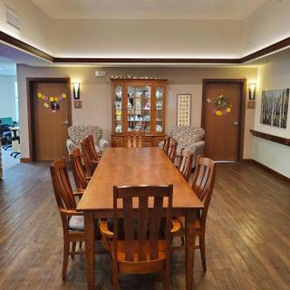 A cozy dining room with a large wooden table surrounded by chairs, featuring warm lighting and elegant decor.