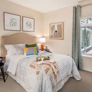 A cozy and well-decorated bedroom with a neatly made bed, colorful pillows, and framed artwork on the walls.