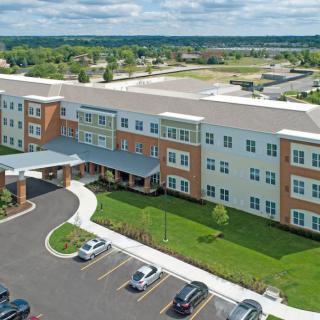Aerial view of a modern residential building with a parking lot and landscaped surroundings.