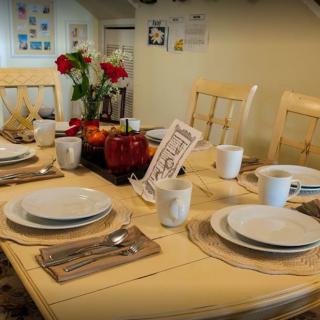 A warmly set dining table with plates, cups, and a floral centerpiece.