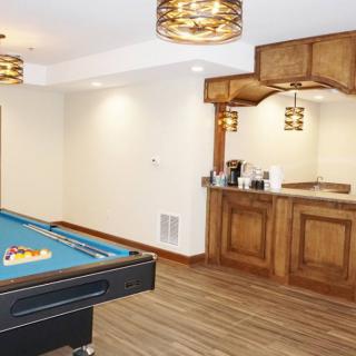 A cozy basement featuring a pool table and a wooden bar, perfect for recreation and entertainment.